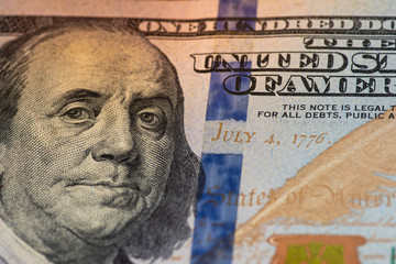 one hundred dollar bill with a lit face on a wooden background