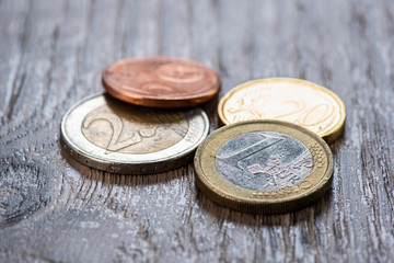 Euro coins and one hundred dollars on a wooden background