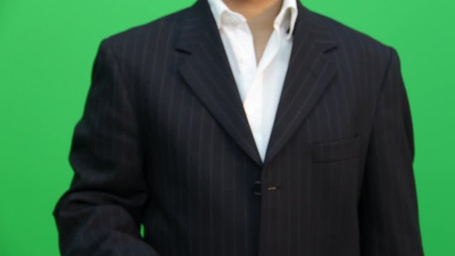 man in a dark, elegant suit, and on green screen for chroma, makes expressions with his hand, touching, moving, executing ideal actions to place objects and designs