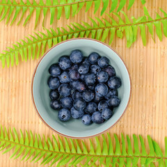 Freshly picked blueberries in bowl. Juicy and fresh blueberry with green leaves on rustic table. Bilberry on wooden Background. sparkleberry antioxidant. Concept for healthy eating