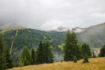 The peaks of the Dolomites in Italy are covered in fog. Early wet foggy morning. Beginning of autumn. Clean fresh air, lack of people. Selective focus.