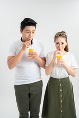 Fototapeta premium Happy young couple with glasses of orange juice isolated on a white background.