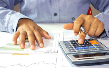 Close-up of a woman examining an accounting report and using a calculator for financial auditing...