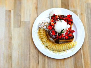 Sweet Dessert, Strawberry nutella chocolate honey toast with vanilla ice cream, sliced bananas and strawberries added topping whipped cream in a white plate isolated on a wooden table background.