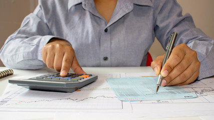 Close-up of a woman examining an accounting report and using a calculator for financial auditing...