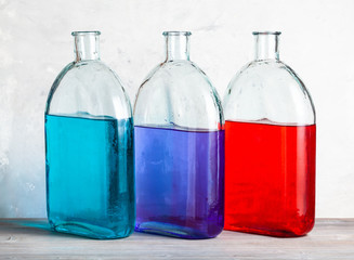 three bottles with color ink solutions on gray