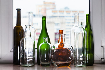 different empty bottles on sill and view of city
