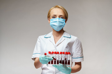 medical doctor nurse woman wearing protective mask and gloves - holding rack with virus blood tests