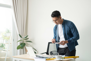 Profile shot of a young male architect working on blueprints at his desk at the office copyspace building plans construction project engineer expert specialist qualified job occupation