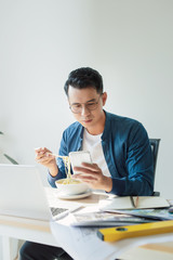 The young beautiful architect eating noodle between working on project, busy office hour.