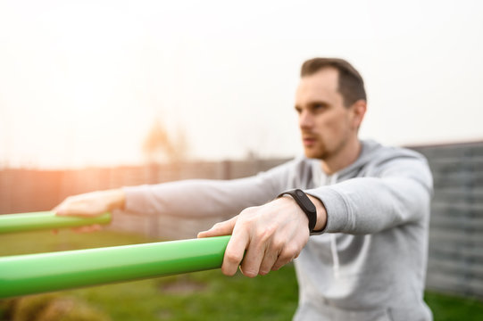 Athletic young man is going to do exercises on parallel bars outdoors. Healthy lifestyle concept