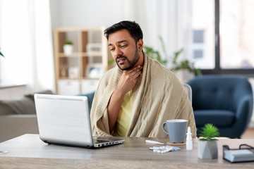 healthcare, technology and people concept - sick indian man in blanket with sore throat having...