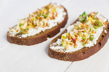 Close up of sandwiches on rye bread with cream cheese and sprouted mung beans, walnut, sunflower and flax. Macrobiotic healthy breakfast.