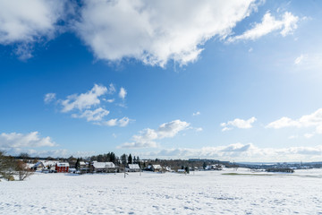 Panorama of beautiful winter town, snow-covered land under blue sky and white clouds