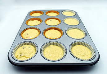 Muffin pan with uncooked muffins isolated on white 