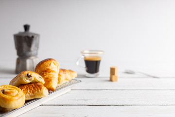 Breakfast table with croissants and cinnamon buns with fresh orange juice.
