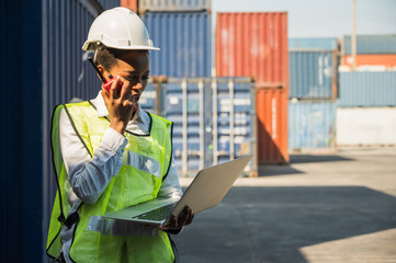 Black foreman woman worker working checking at Container cargo harbor holding laptop computer and...