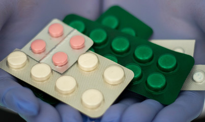 doctor in blue medical gloves holding colored pills close up 