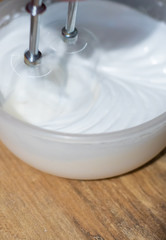 The baker stirs the egg whites with a mixer. Preparing dessert for Easter