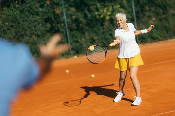 Tennis instructor with senior woman, tennis training lesson