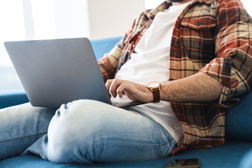 Portrait of caucasian man using laptop while sitting on sofa at home