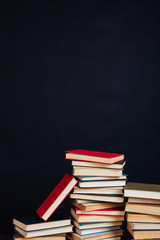 many stacks of educational books in the university library on a black background