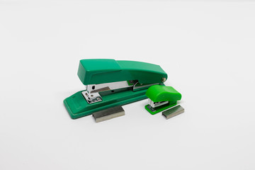 Two green plastic and metal staplers with staples, small and medium size, isolated on white background. Top view, closeup. Office idea concept.