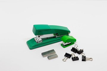 Green plastic and metal staplers with staples, binder clips isolated on white background. Top view,...
