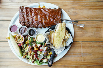 Delicious barbecued ribs seasoned with a sauce. BBQ Ribs served with fresh vegetables on white...
