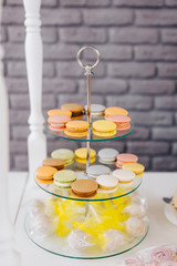 sweet multicolored candies on a stand stand on a table against a gray wall
