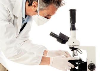 A doctor with mask and gloves working at the microscope