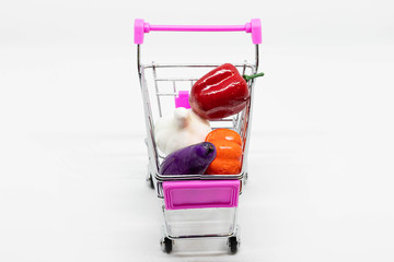 Toy colorful vegetables in full self-service shopping cart isolated on white background. Top view,...