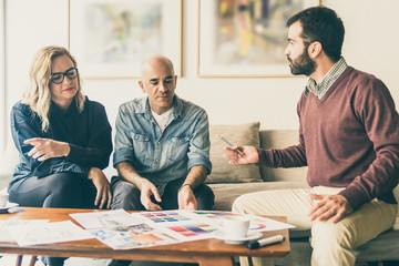 Mature owners choosing color for renovation. Mature woman and men sitting in living room at home and talking. Renovation concept