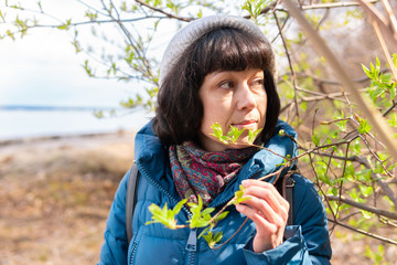 A beautiful woman in a jacket walks in a spring Park by the river