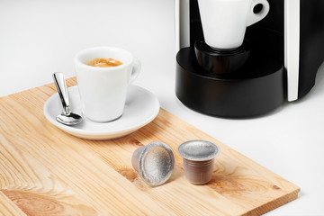 Espresso coffee and coffee pods on wood tray. Espresso machine on the background