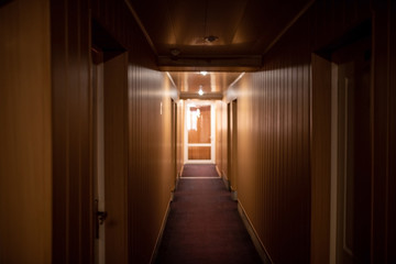 Corridor in a small hotel with brown walls.