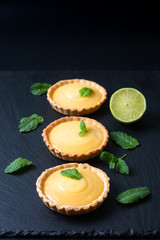 Obraz na płótnie Canvas Food concept Homemade organic Lemon, lime tarts or mini pie on black slate stone board
