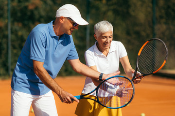 Tennis Instructor with Senior Woman on Clay Court. Woman having a Tennis Lesson.
