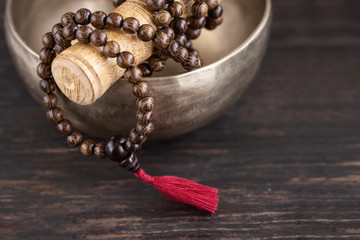 Detail of mala beads into the Tibetan singing bowl  on wooden background .Toned image
