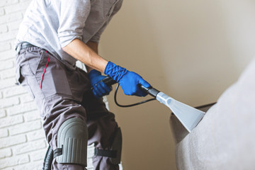 Man cleaning sofa chemical cleaning with professionally extraction method. Upholstered furniture. Early spring cleaning or regular clean up.