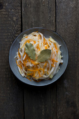 fermented white cabbage on a gray plate on a wooden background, top view