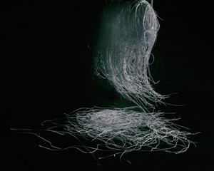 Light blue tangled threads hang and fall on a black background. Suitable as an abstract background, advertising