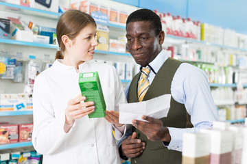 Woman pharmacist talking with man client, picking up prescription