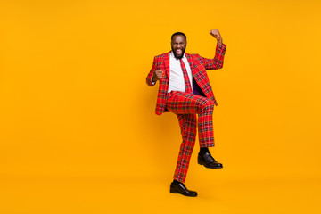 Full length photo of crazy dark skin guy raise fists leg celebrate successful achievement wear plaid red costume blazer pants shoes isolated bright yellow color background