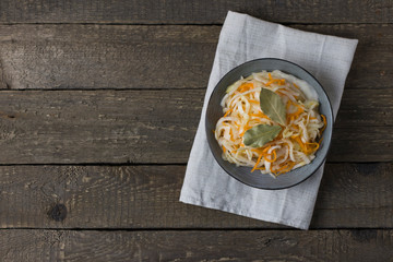 fermented white cabbage on a gray plate on a wooden background, top view