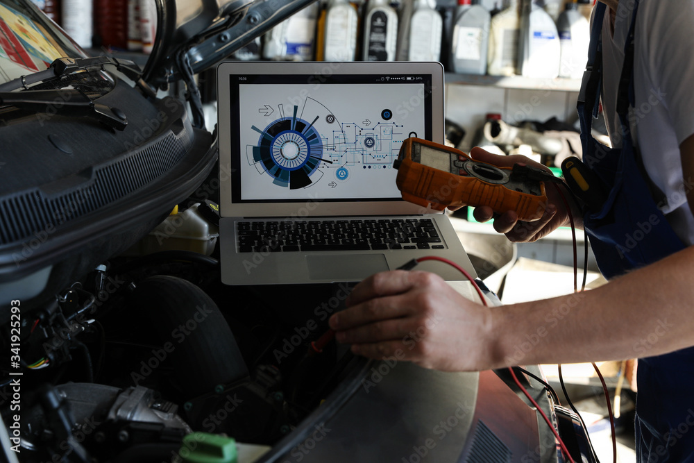 Poster Mechanic with laptop doing car diagnostic at automobile repair shop, closeup