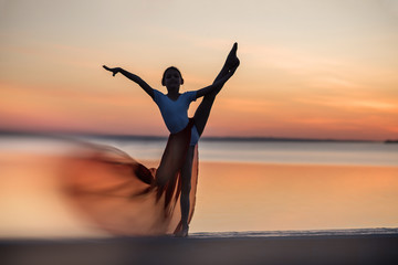 Fototapeta premium silhouette of a woman doing yoga on the beach