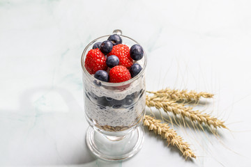 Muesli with berries and chia seeds on a light marble table