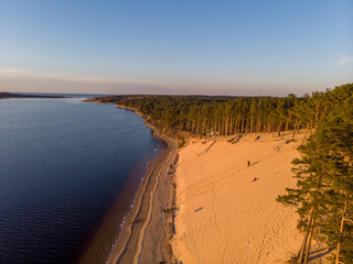 Beautiful drone areal photography view of large dune and pine forest near river Lielupe. Photo taken on sunset.
