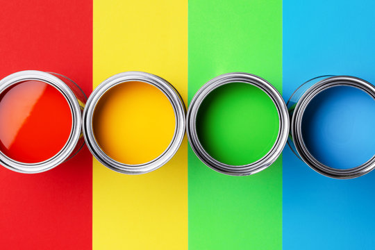 Row Of Cans Of Colorful Paint On Colorful Background. Top View On Red, Yellow, Green And Blue Paints.